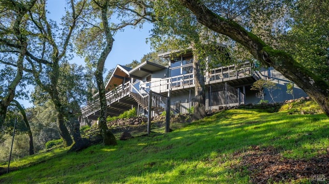 rear view of house with a wooden deck and a lawn