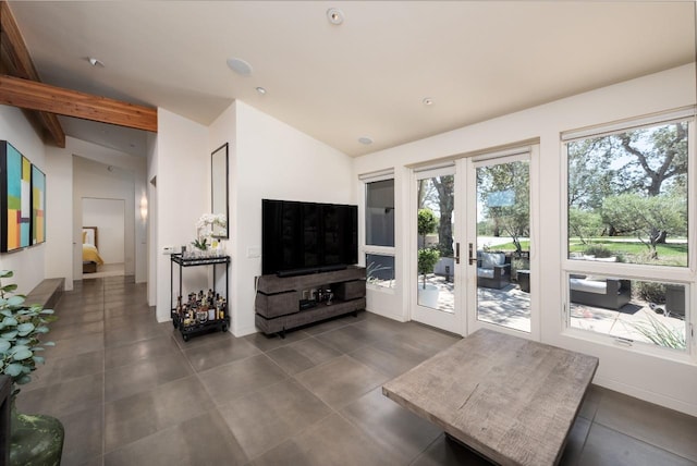 living area with a wealth of natural light, dark tile patterned flooring, and lofted ceiling with beams