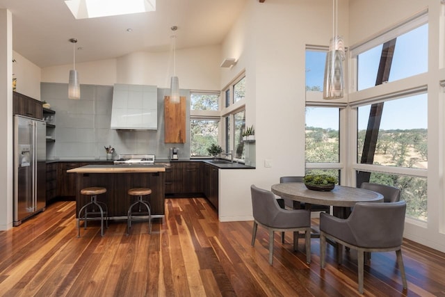 kitchen with premium range hood, high vaulted ceiling, high end fridge, and a skylight