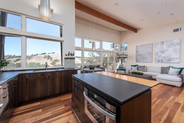 kitchen featuring dark countertops, beam ceiling, visible vents, and a sink
