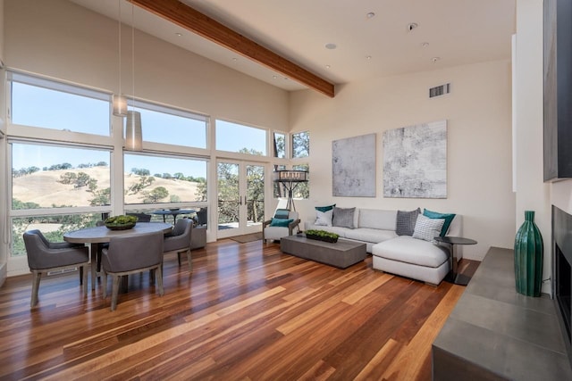 living area featuring wood finished floors, visible vents, a high ceiling, french doors, and beamed ceiling