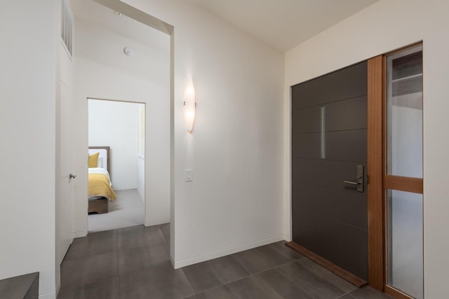 foyer with baseboards and dark tile patterned floors