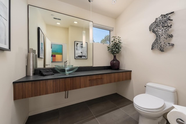 half bathroom with vanity, tile patterned floors, toilet, and visible vents