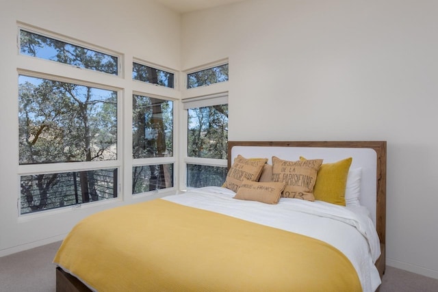 carpeted bedroom with baseboards and a towering ceiling