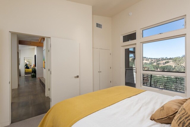 bedroom with multiple windows, visible vents, and a towering ceiling