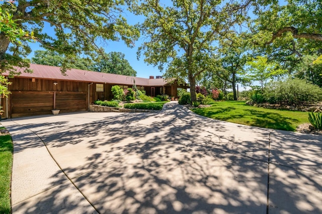 single story home with concrete driveway and a front yard