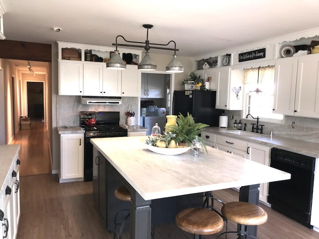 kitchen featuring black appliances, light countertops, under cabinet range hood, and a sink