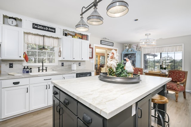 kitchen with white cabinets, light wood-type flooring, and a sink