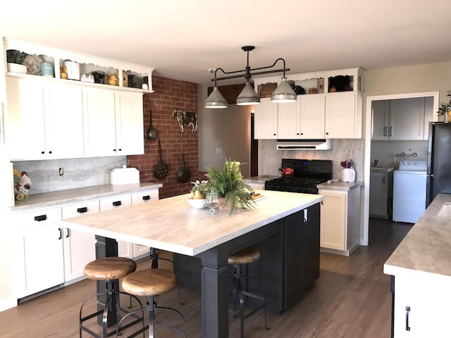 kitchen featuring black appliances, washer / clothes dryer, white cabinetry, light countertops, and extractor fan