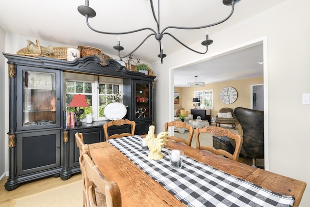 dining space with light wood-style floors and an inviting chandelier