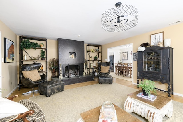 living room with a large fireplace, baseboards, visible vents, and wood finished floors