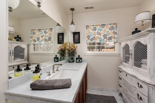 bathroom featuring visible vents, baseboards, a healthy amount of sunlight, and vanity