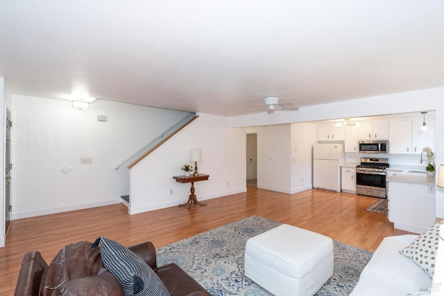 living room with ceiling fan, sink, and light hardwood / wood-style floors