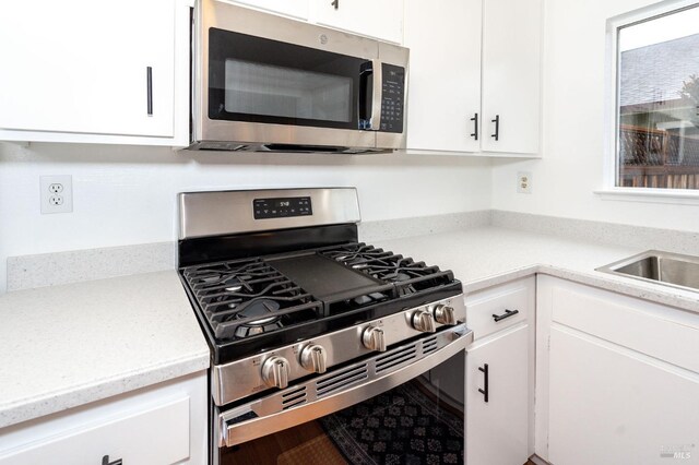 kitchen with stainless steel appliances, sink, and white cabinets