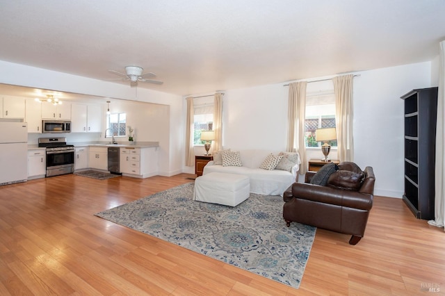 living room with ceiling fan, sink, and light hardwood / wood-style flooring