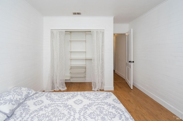 bedroom featuring light hardwood / wood-style flooring, ornamental molding, and a closet