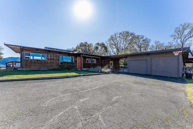 view of front facade featuring a carport, a front yard, driveway, and an attached garage