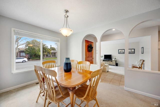 dining area with light colored carpet and a textured ceiling