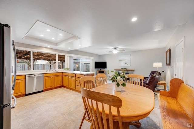 dining room with ceiling fan, a tray ceiling, and sink