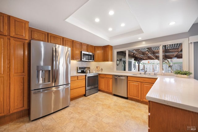 kitchen featuring sink, a tray ceiling, stainless steel appliances, and backsplash