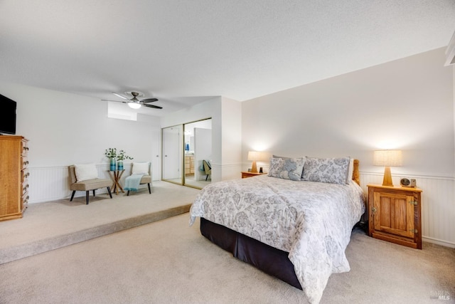 bedroom featuring light carpet, a textured ceiling, ceiling fan, and a closet