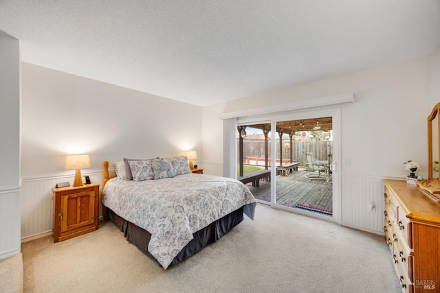 bedroom with access to outside, light colored carpet, and a textured ceiling