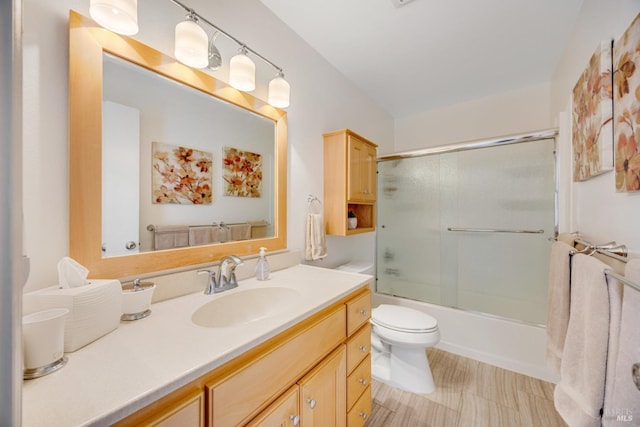 full bathroom featuring vanity, shower / bath combination with glass door, and toilet