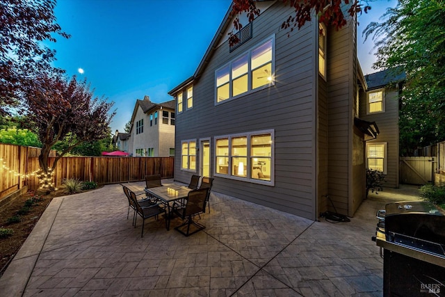 back house at dusk with a patio