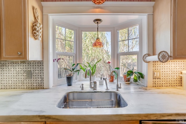 kitchen with sink, hanging light fixtures, dishwasher, light stone countertops, and decorative backsplash