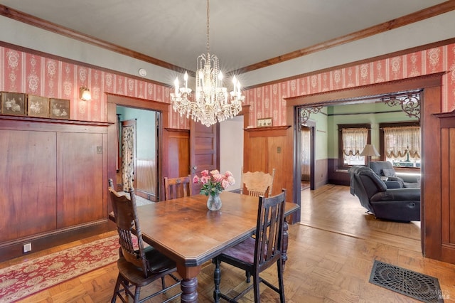 dining space with crown molding, parquet flooring, and a notable chandelier