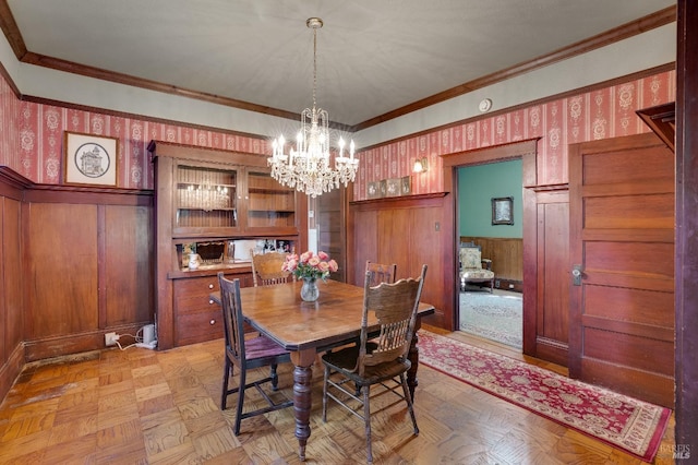 dining space featuring light parquet floors, ornamental molding, and a chandelier