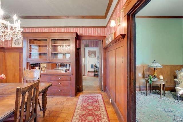 dining space with ornamental molding, light parquet flooring, and an inviting chandelier