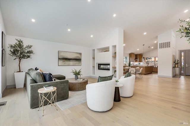 living room with a multi sided fireplace, high vaulted ceiling, light hardwood / wood-style flooring, and built in features