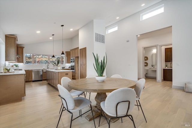 dining room featuring sink, light hardwood / wood-style floors, and high vaulted ceiling