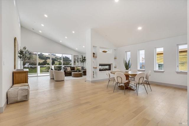 dining area featuring a wealth of natural light, light hardwood / wood-style flooring, and high vaulted ceiling