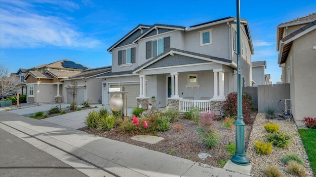 craftsman house featuring stucco siding, concrete driveway, covered porch, fence, and a garage