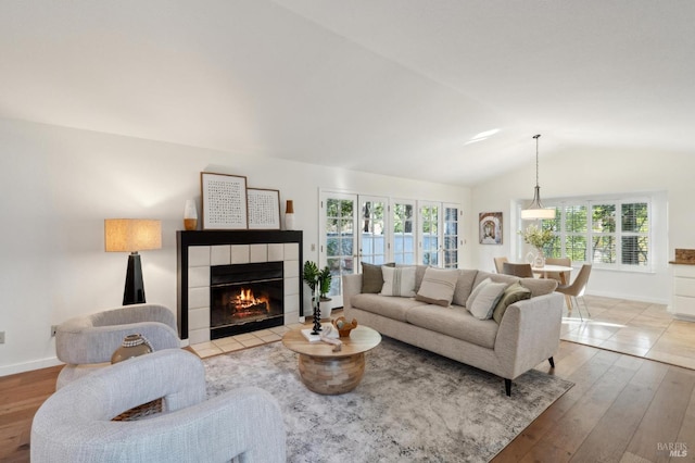 living room with a fireplace, light hardwood / wood-style floors, and vaulted ceiling