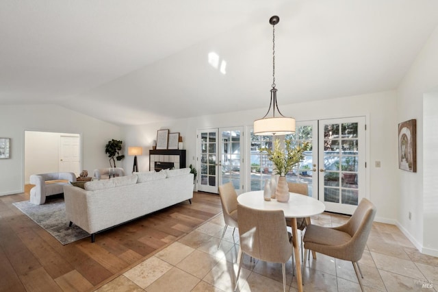 dining area with french doors, lofted ceiling, and light hardwood / wood-style flooring