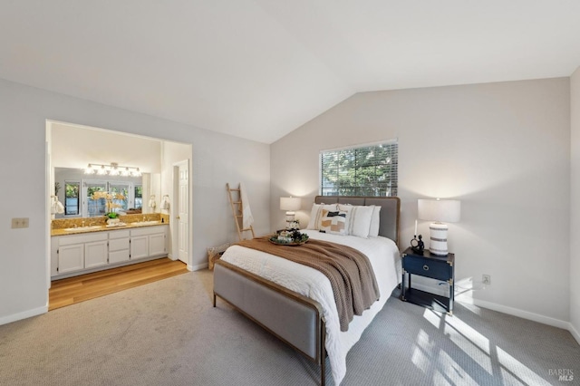 bedroom featuring lofted ceiling, connected bathroom, and light carpet