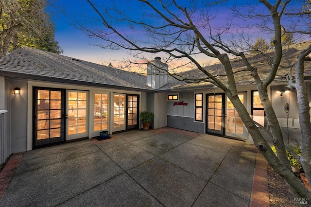 back house at dusk with a patio area