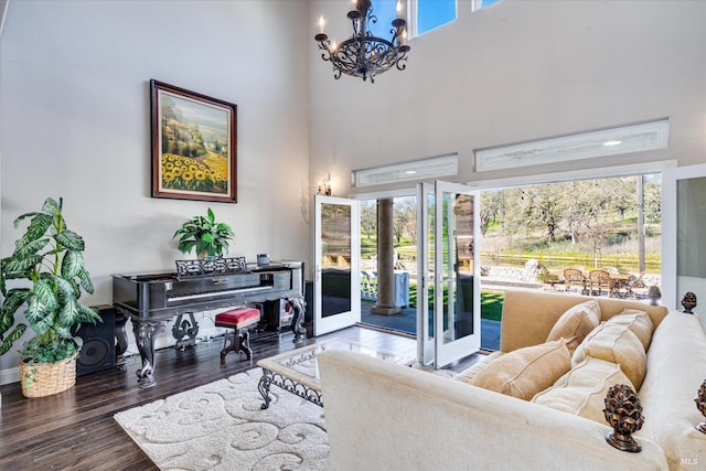 living room with a high ceiling, a healthy amount of sunlight, dark hardwood / wood-style floors, and a chandelier