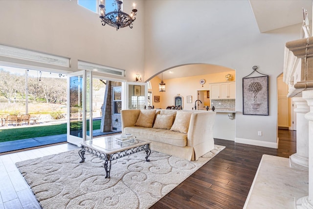 living room featuring a notable chandelier, a towering ceiling, and dark hardwood / wood-style floors