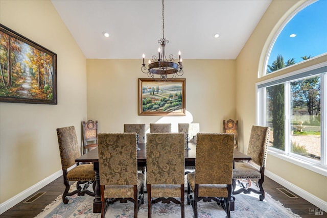 dining area with hardwood / wood-style flooring, vaulted ceiling, and an inviting chandelier