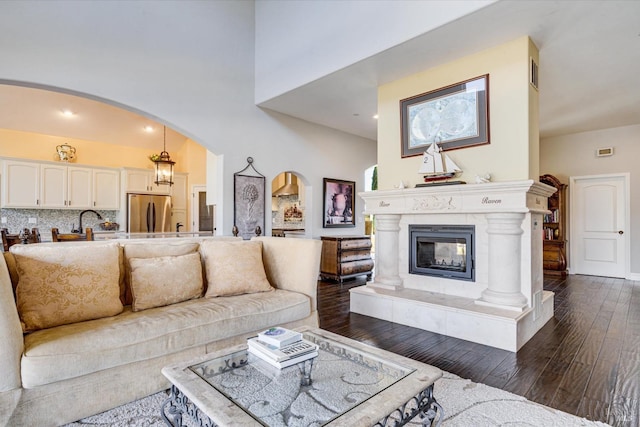 living room featuring a high ceiling, sink, a fireplace, and dark hardwood / wood-style flooring