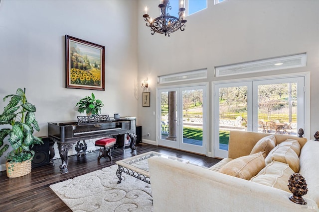 interior space with an inviting chandelier, a towering ceiling, dark hardwood / wood-style floors, and french doors