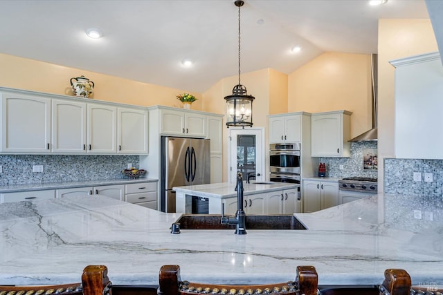 kitchen featuring pendant lighting, white cabinetry, stainless steel appliances, a kitchen breakfast bar, and light stone counters