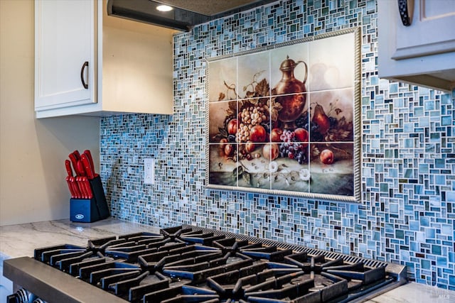 details with tasteful backsplash, stovetop, and white cabinets