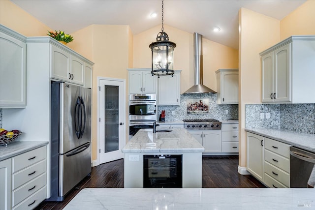 kitchen with wine cooler, hanging light fixtures, appliances with stainless steel finishes, light stone countertops, and wall chimney range hood