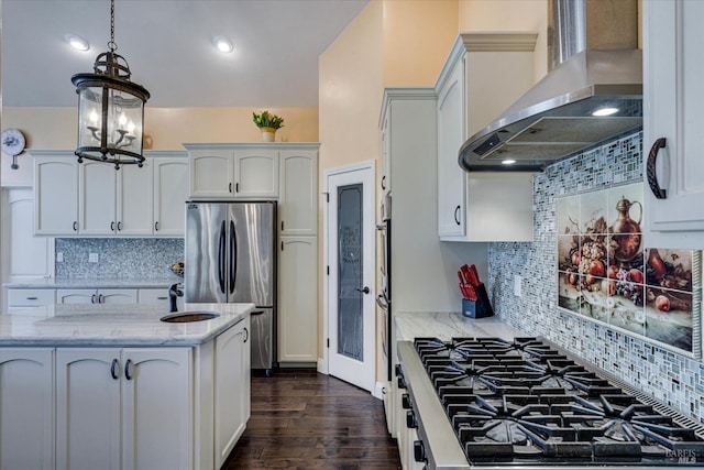 kitchen featuring cooktop, stainless steel refrigerator, pendant lighting, light stone countertops, and wall chimney range hood