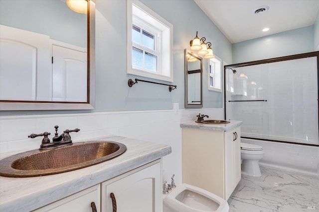 full bathroom with a bidet, vanity, shower / bath combination with glass door, and toilet